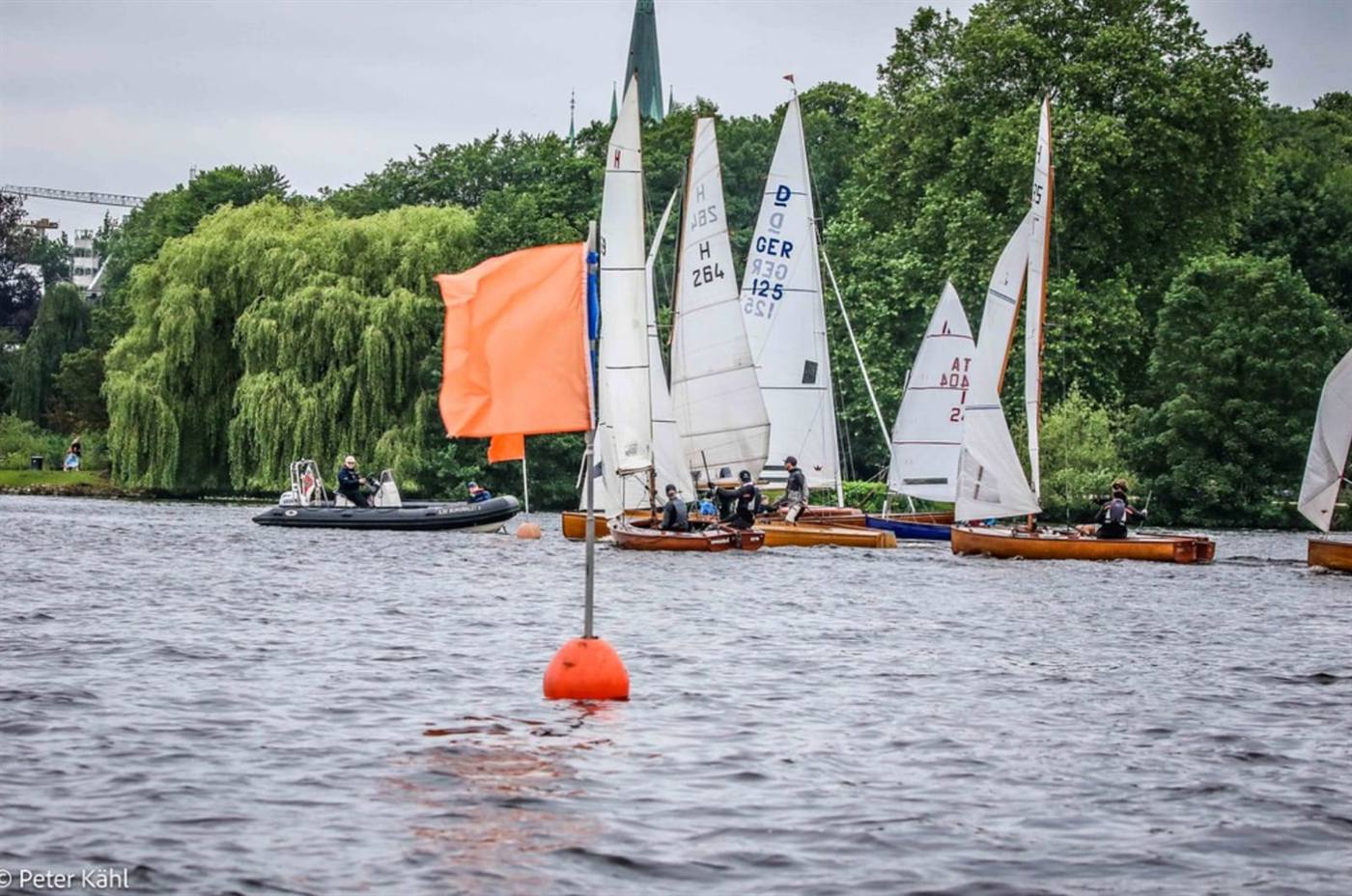 Club dinghies rounding an orange mark buoy, with the committee boat standing by.